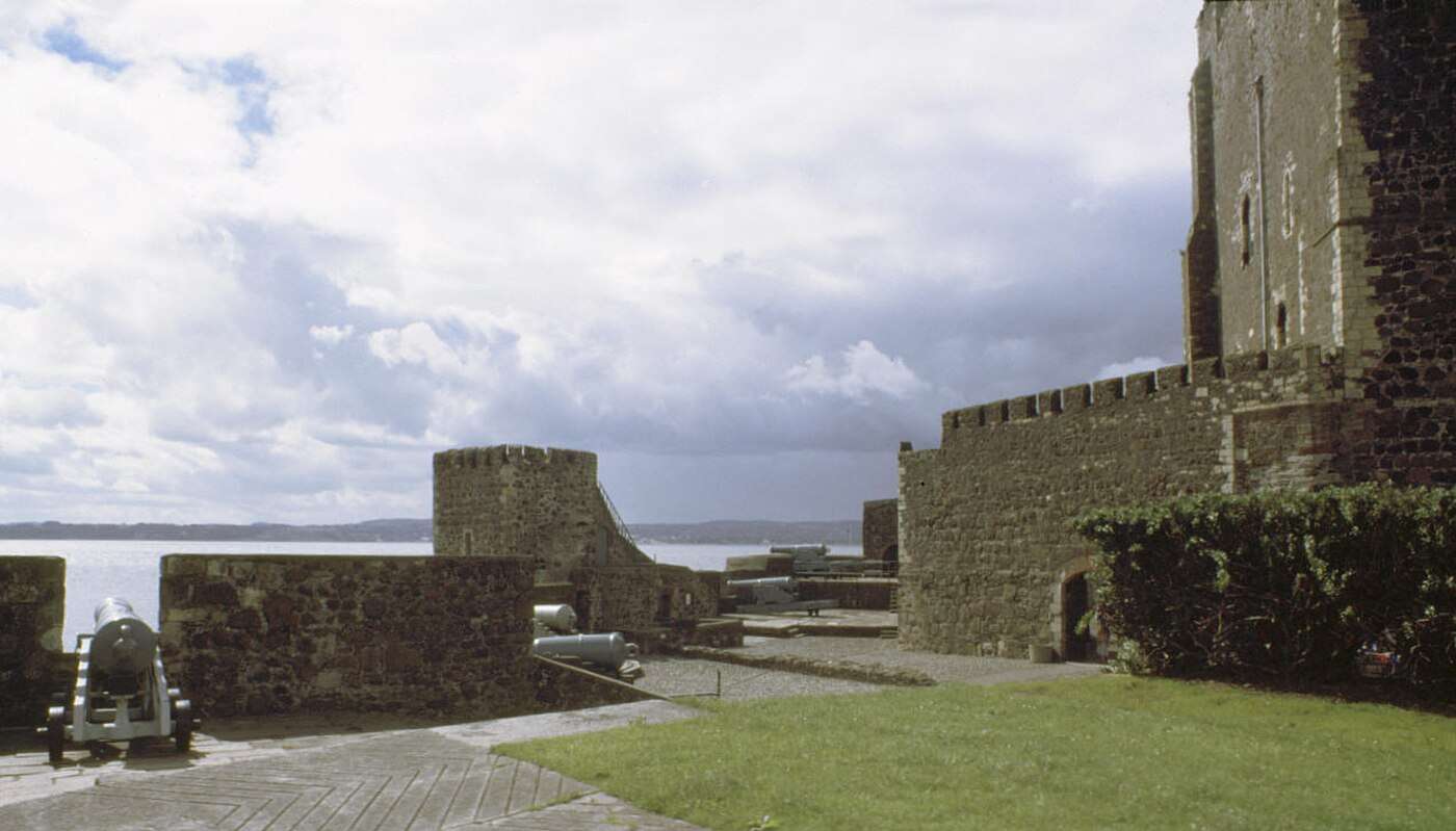 Cannon on the ramparts inside Carrickfergus Castle, with the keep at right and Belfast Lough beyond